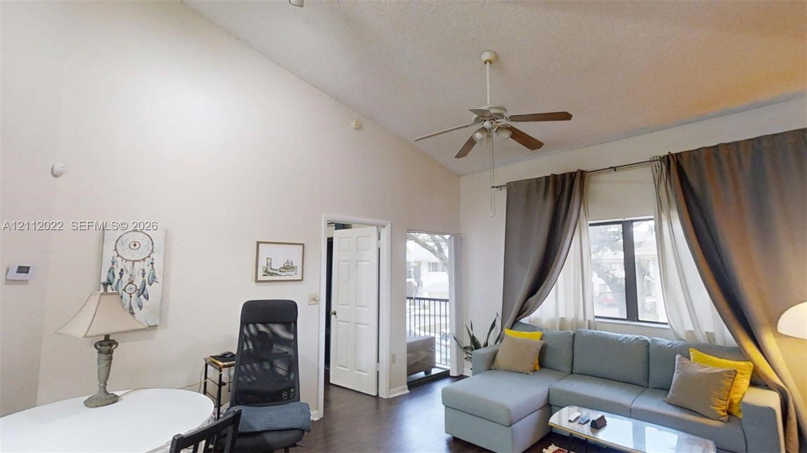 Vaulted ceiling, ceiling fan with light fixture, and wood-finish flooring