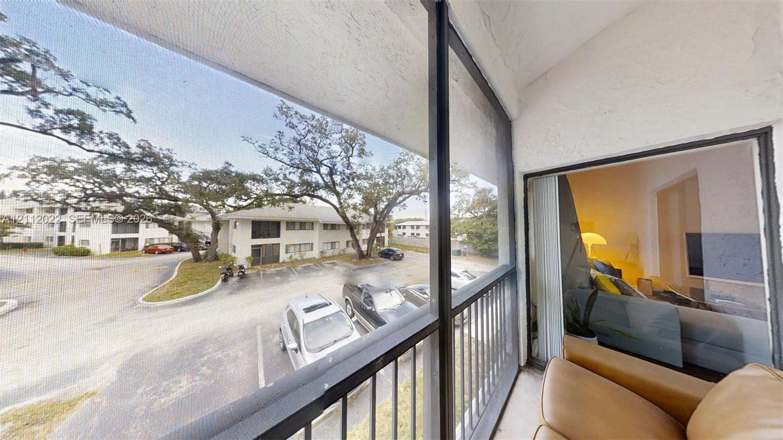 Screened balcony featuring a metal railing and sliding glass door entrance
