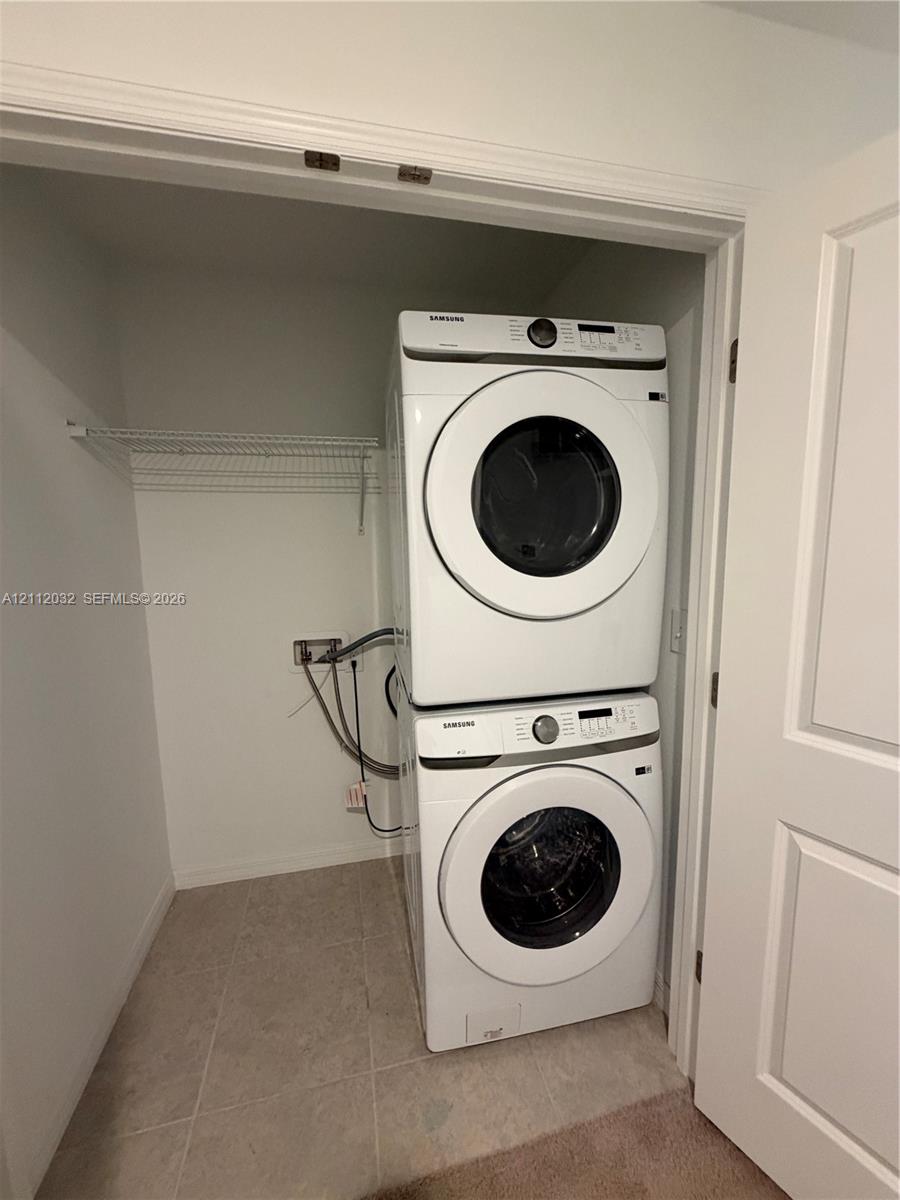 Stacked laundry appliances with wire shelving in a dedicated enclosure