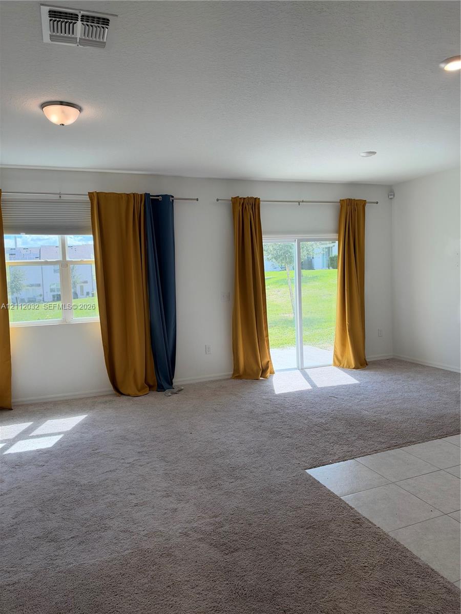 Interior space featuring wall-to-wall carpeting, tile flooring, flush-mount lighting fixtures, and a sliding glass door