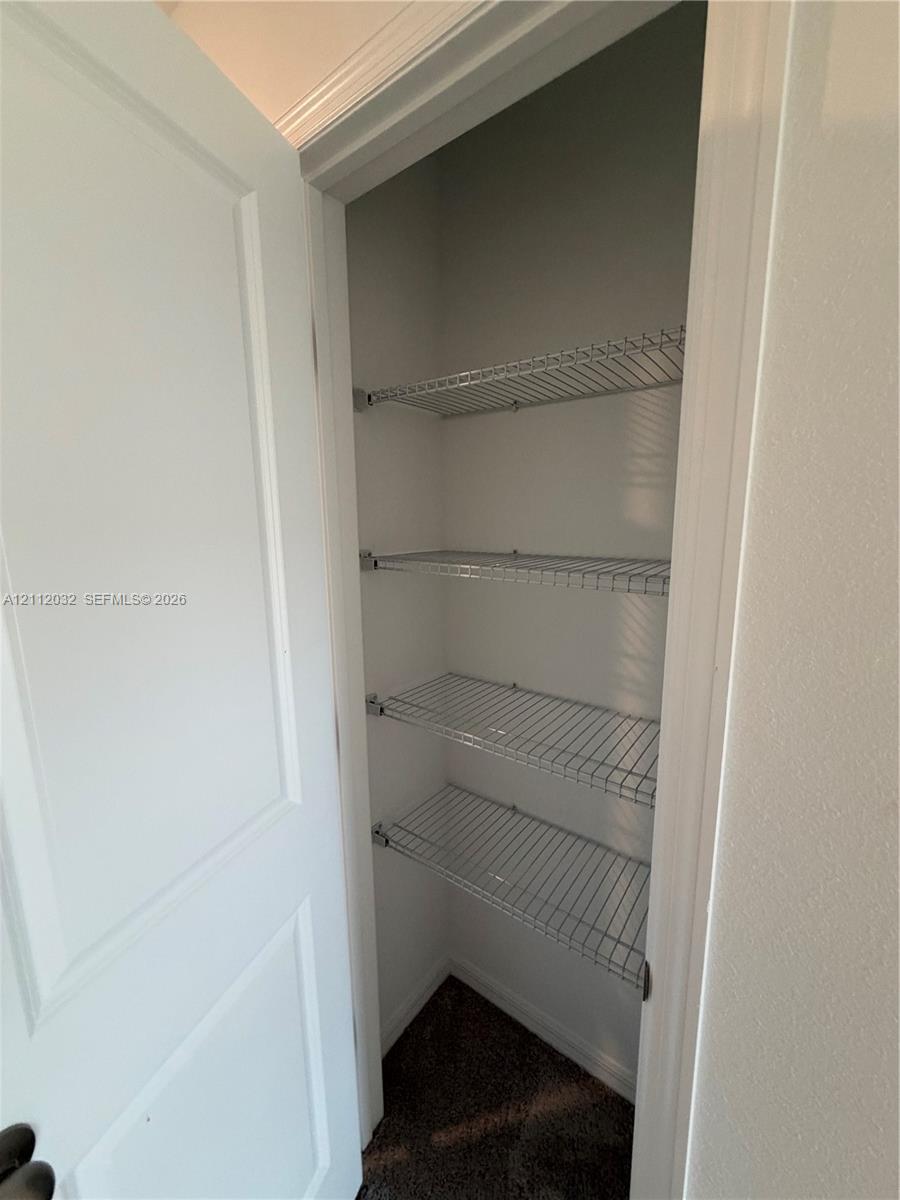 Built-in storage closet featuring four tiered wire shelves and a solid-core hinged door