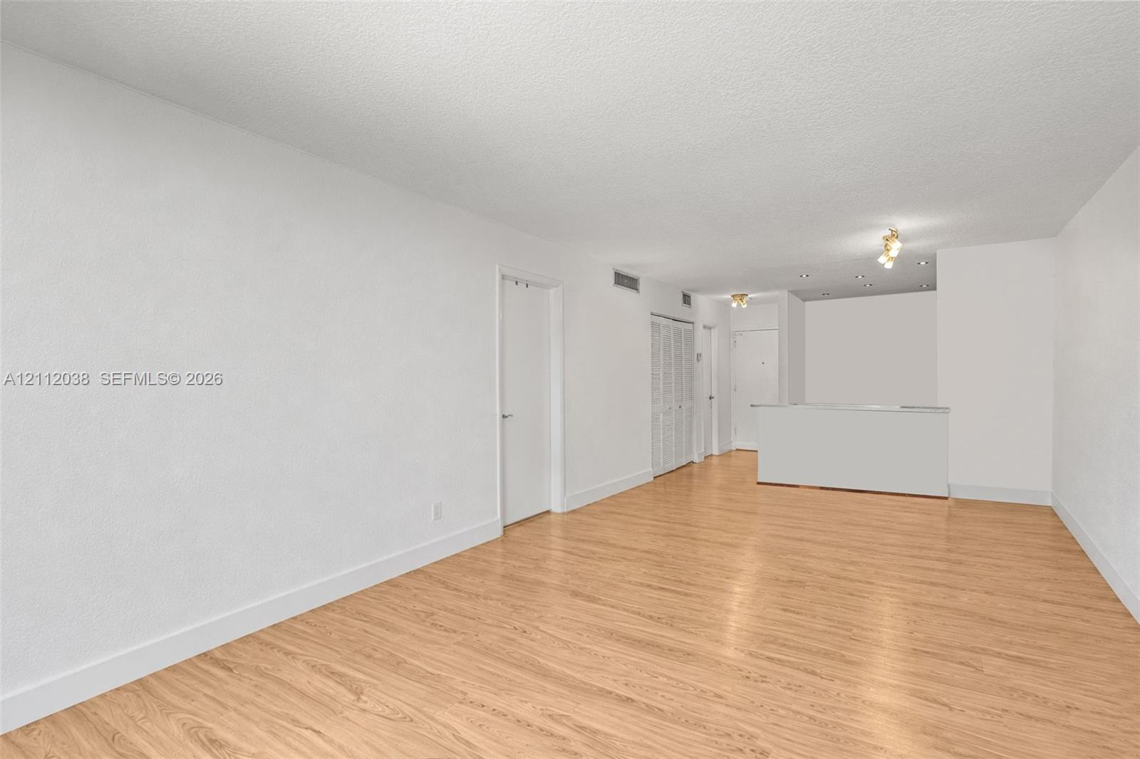 Interior space featuring wood-finish flooring, white walls, built-in cabinetry with louvered doors, and recessed ceiling lighting