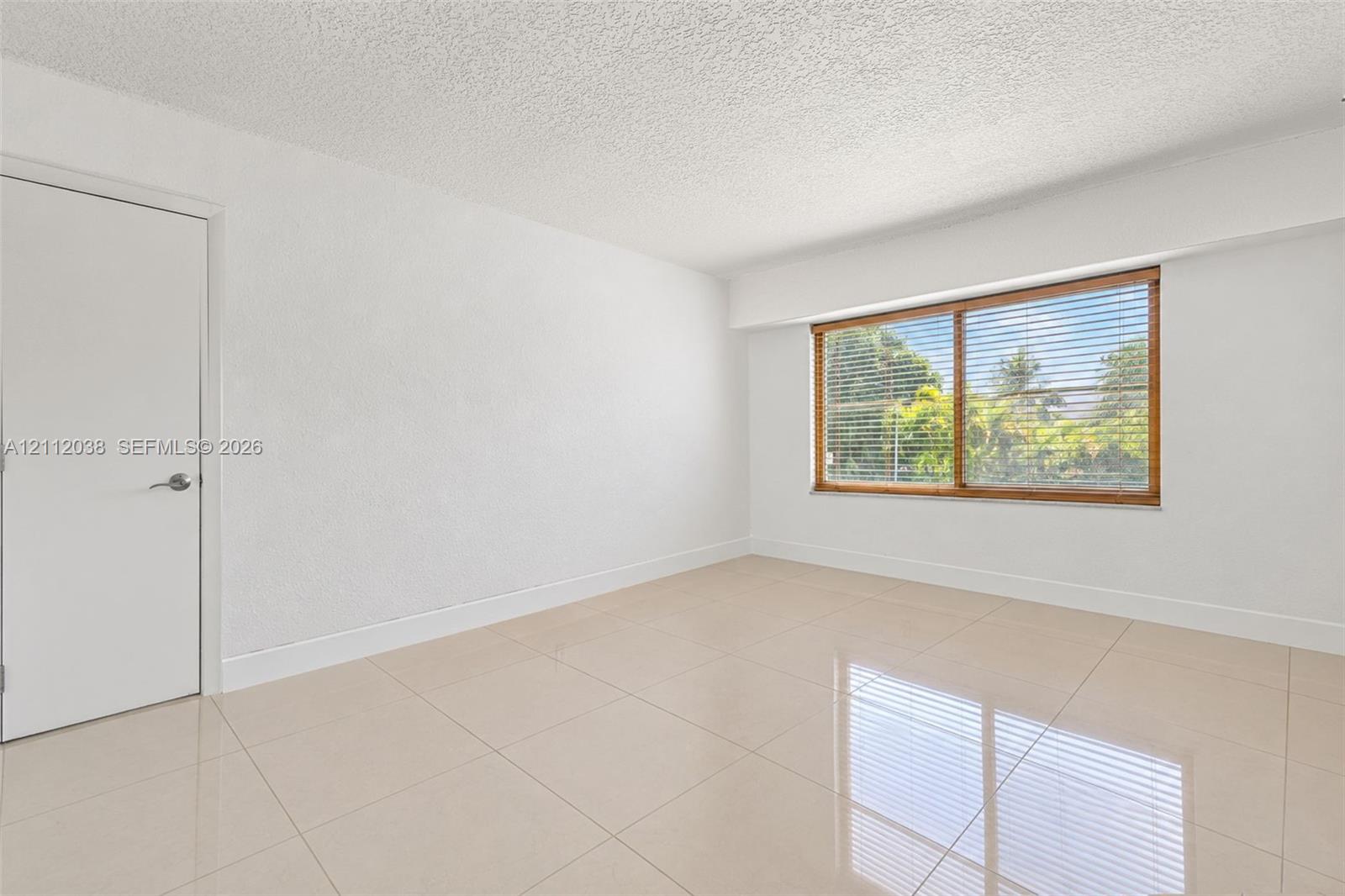 Bright interior space featuring polished tile flooring, smooth wall finishes, and a large window with natural light