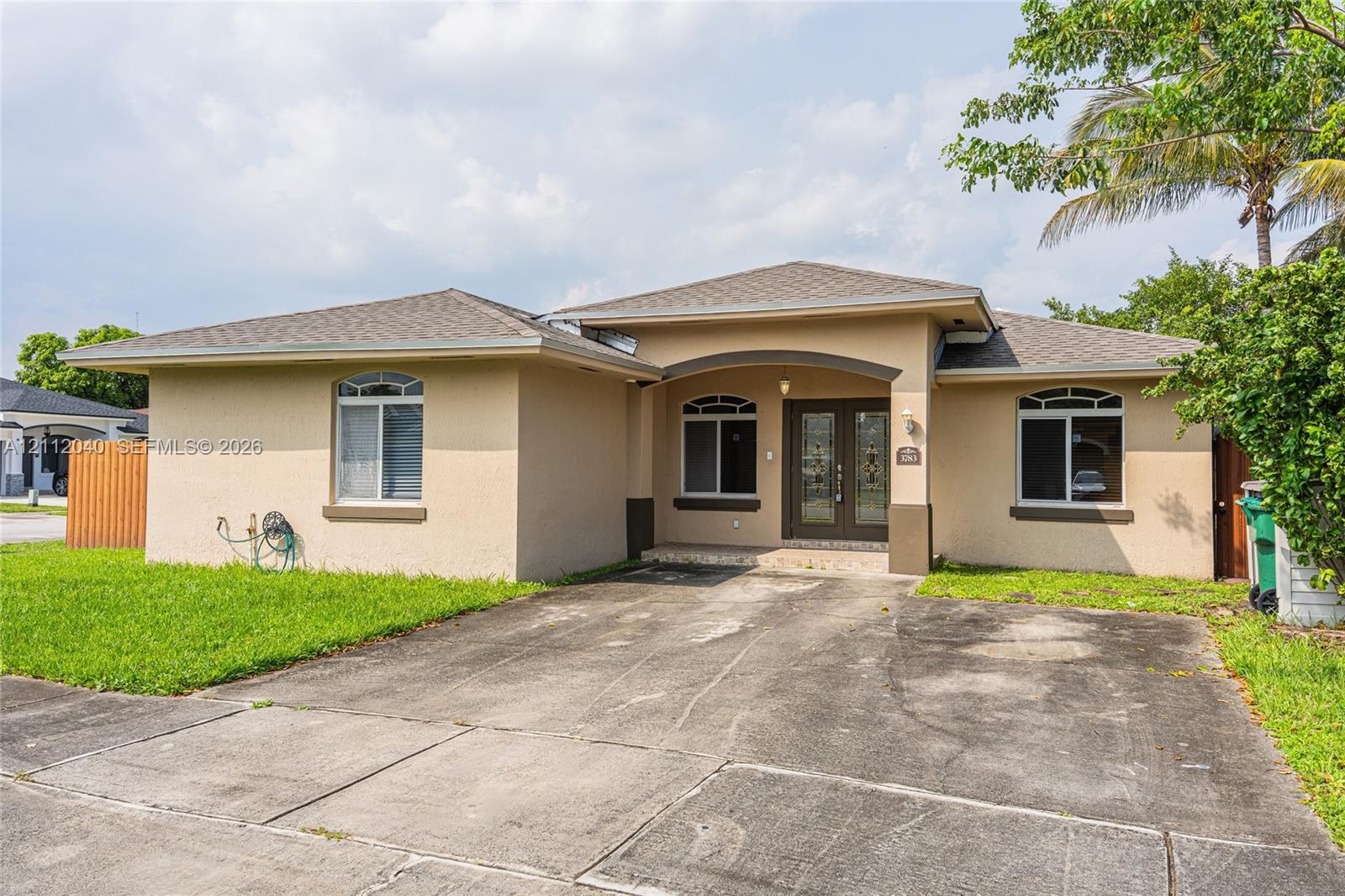 Stucco exterior featuring a hipped roof, arched entryway, double-door entrance, and decorative arched window headers
