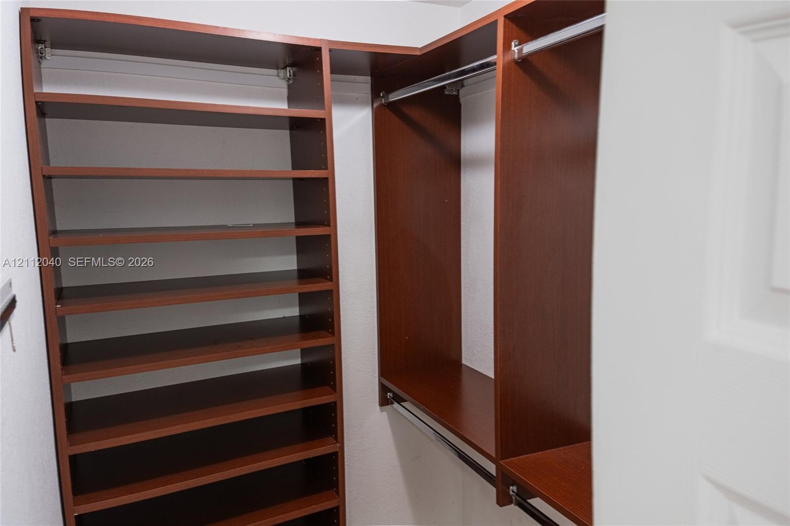 Built-in closet organization system featuring wood-finish cabinetry, adjustable shelving, and integrated metal clothing rods