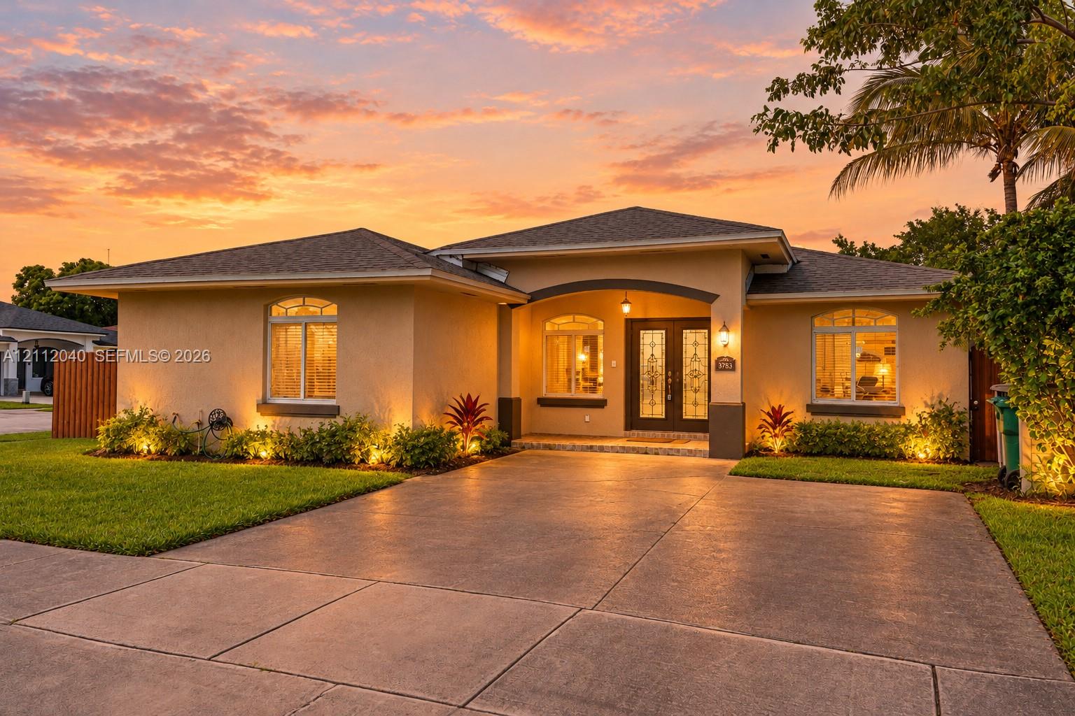 Stucco exterior residence featuring an arched covered entryway, double glass-panel front doors, a concrete driveway, and a shingle roof Stucco exterior residence featuring an arched covered entryway, double glass-panel front doors, a concrete driveway, and a shingle roof