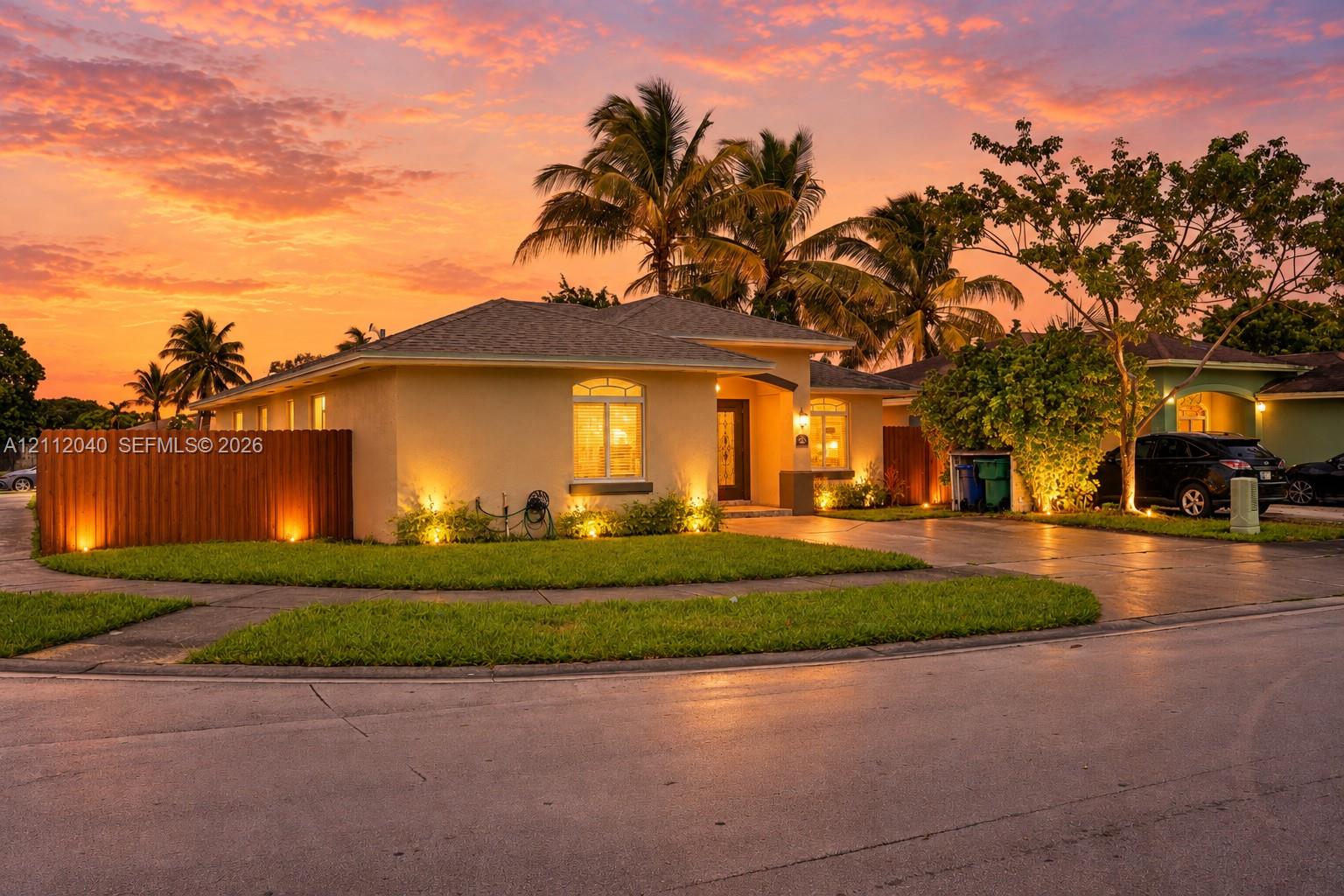 Single-story exterior featuring light-toned stucco siding, an asphalt shingle roof, a paved driveway, and an arched entryway
