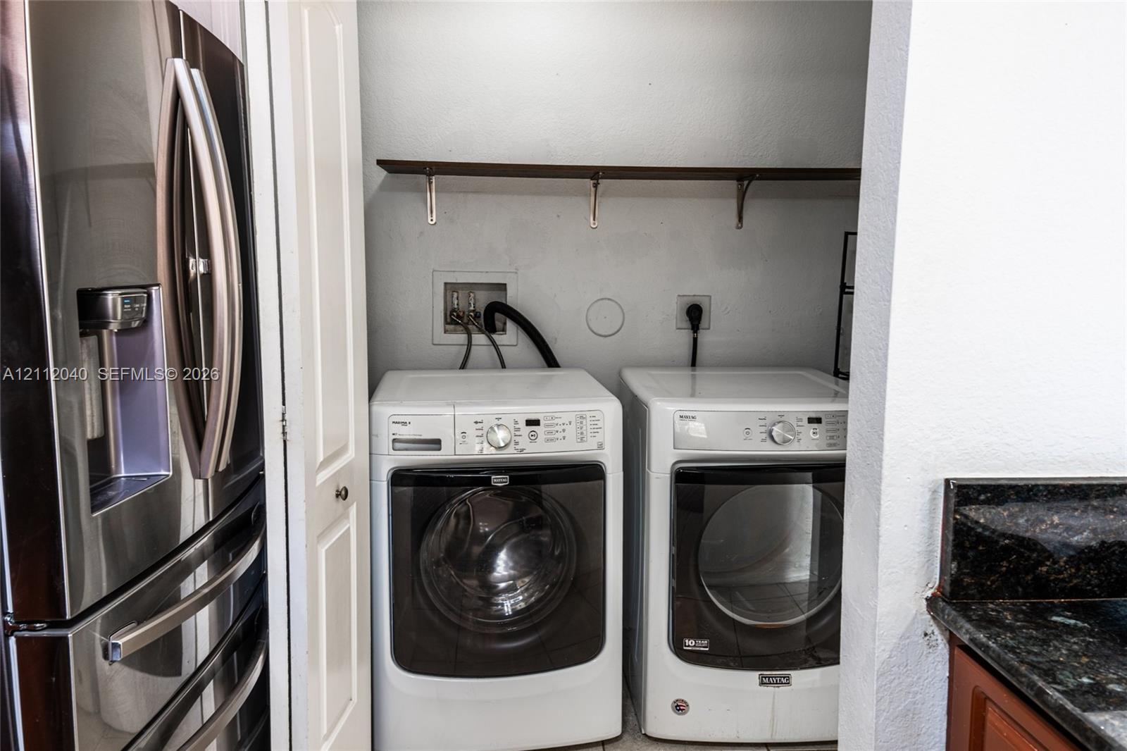 Laundry area featuring white front-loading appliances and a built-in wall-mounted shelving unit