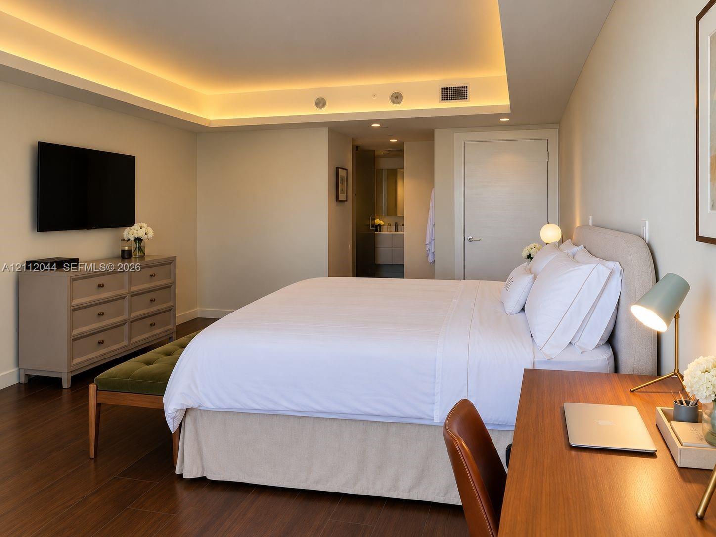 Interior space featuring recessed tray ceiling with integrated cove lighting, wood-finish flooring, and a solid-core interior door