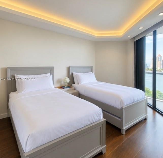 Tray ceiling with integrated cove lighting, wood-finish flooring, and floor-to-ceiling windows