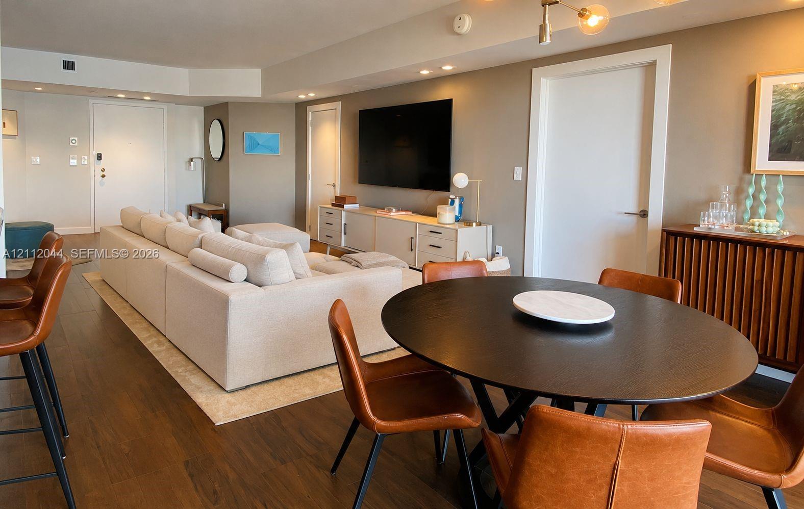 Open-concept interior featuring wood-finish flooring, recessed lighting, and a multi-arm brass chandelier
