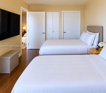 Room featuring wood-finish flooring, dual-door closet storage, and neutral wall tones