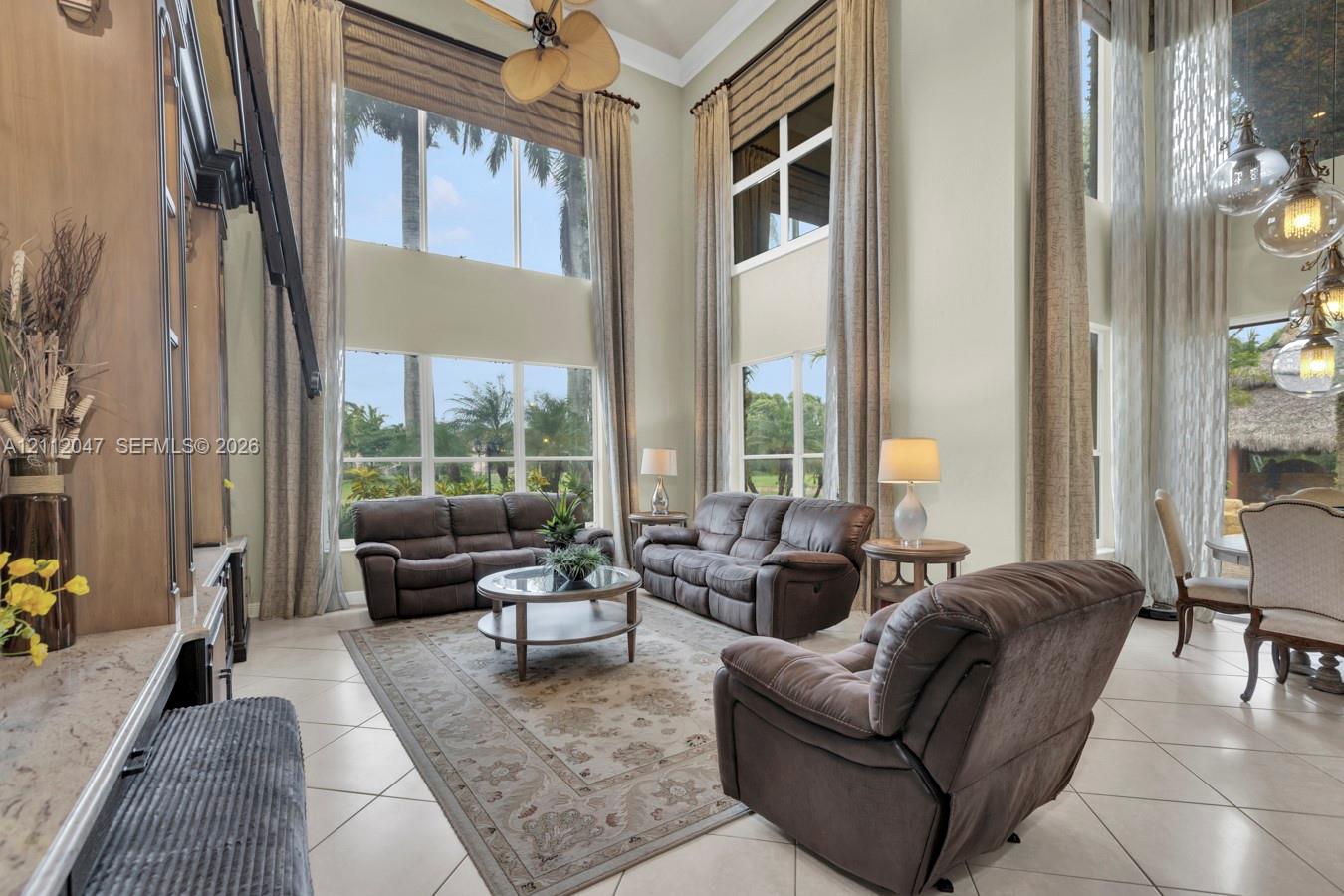 Double-height ceilings, expansive floor-to-ceiling windows, built-in cabinetry, tile flooring, and multi-tier glass globe pendant lighting
