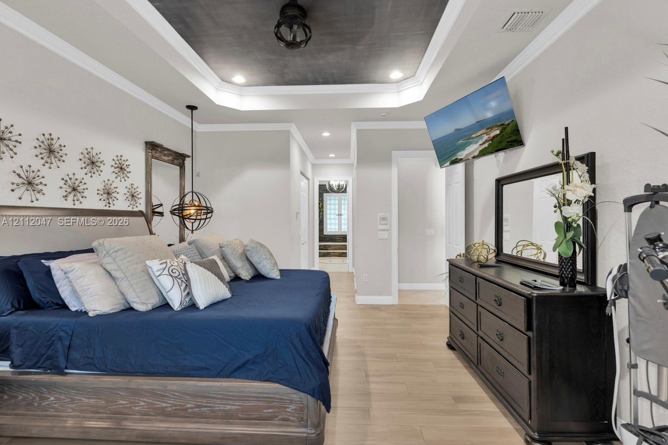 Tray ceiling with dark interior finish, wood-finish flooring, recessed lighting, and spherical metal pendant light