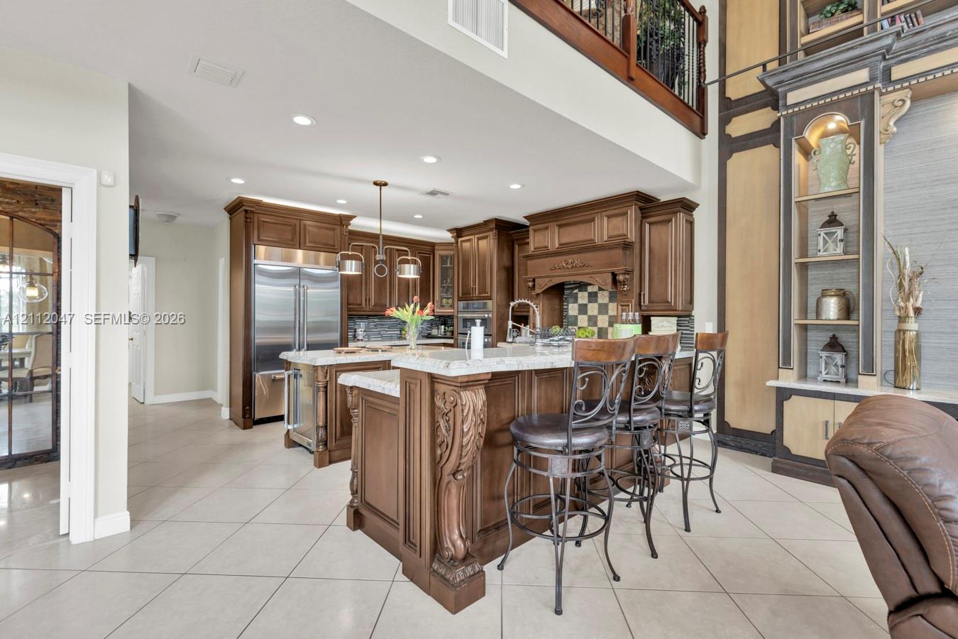 Kitchen featuring stained wood cabinetry, stone countertops, a multi-level breakfast bar with carved corbels, recessed lighting, and stainless steel appliances