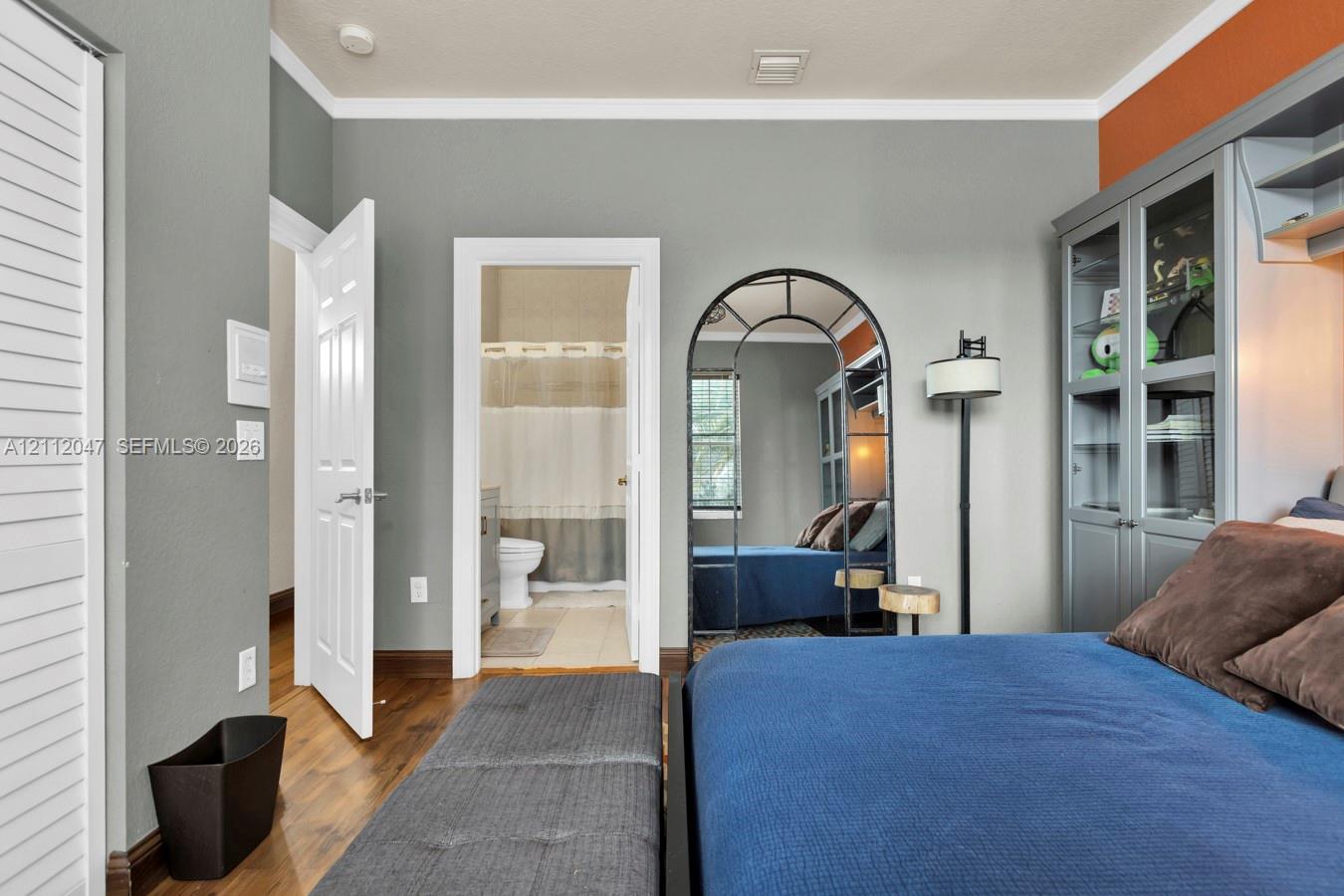 Built-in grey cabinetry with glass-front shelving, wood-finish flooring, and crown molding