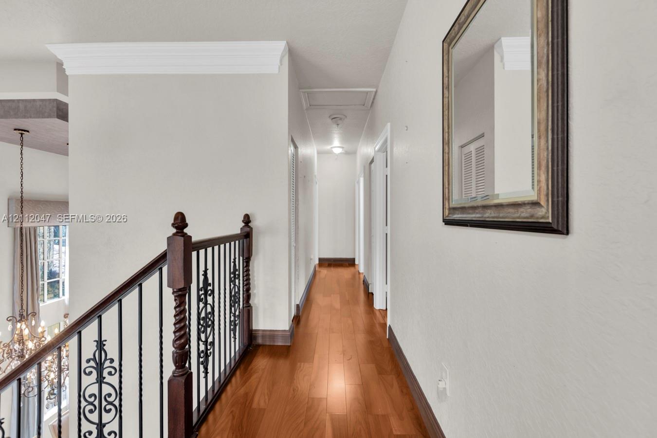 Wood-finish flooring, ornate iron balustrade with decorative posts, and crown molding