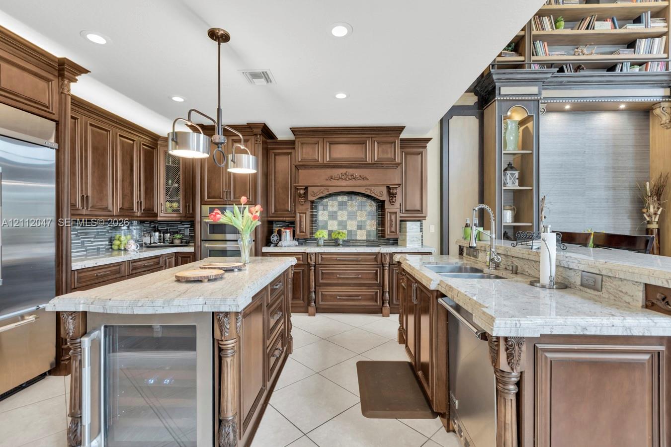 Custom wood cabinetry featuring decorative molding, expansive stone countertops, stainless steel appliances, built-in wine refrigeration, and a tiled backsplash