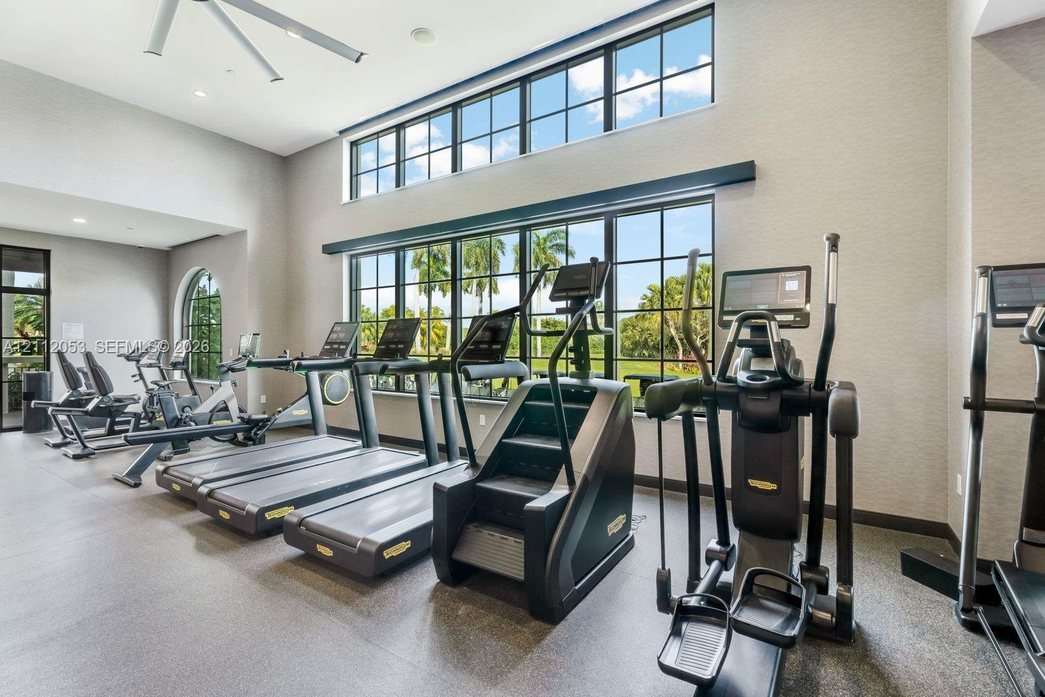 Fitness center featuring high ceilings, oversized black-framed windows, recessed lighting, and industrial-style ceiling fans