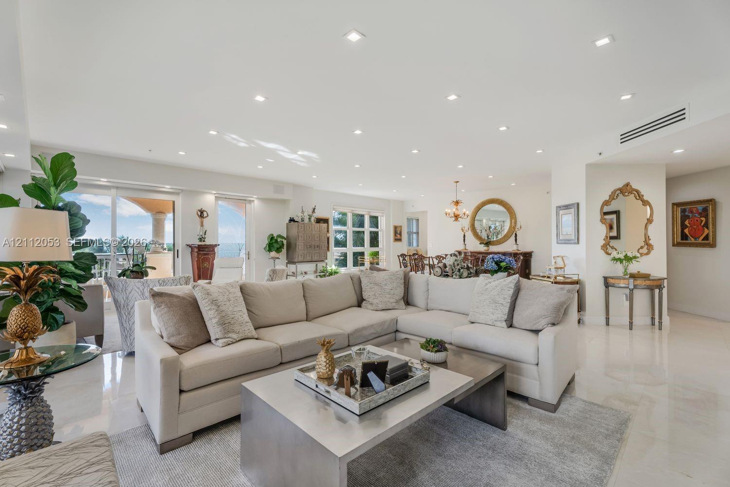 Open-concept living space featuring high ceilings, polished stone-finish flooring, recessed lighting, and expansive glass sliding doors Open-concept living space featuring high ceilings, polished stone-finish flooring, recessed lighting, and expansive glass sliding doors