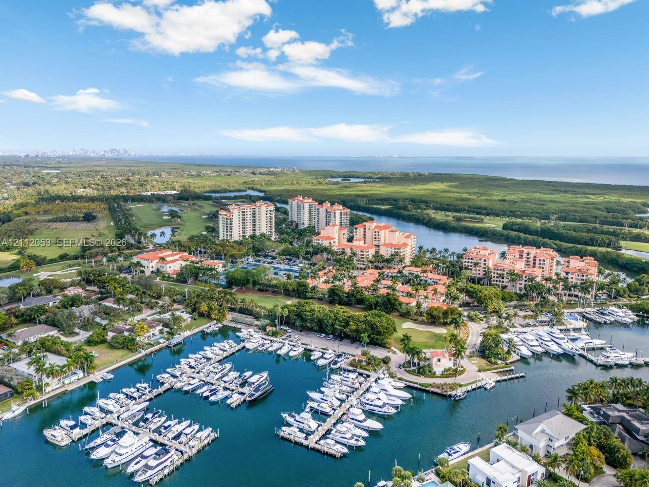 Aerial perspective featuring a private deep-water marina, multi-story residential structures, coastal vegetation, and immediate water access