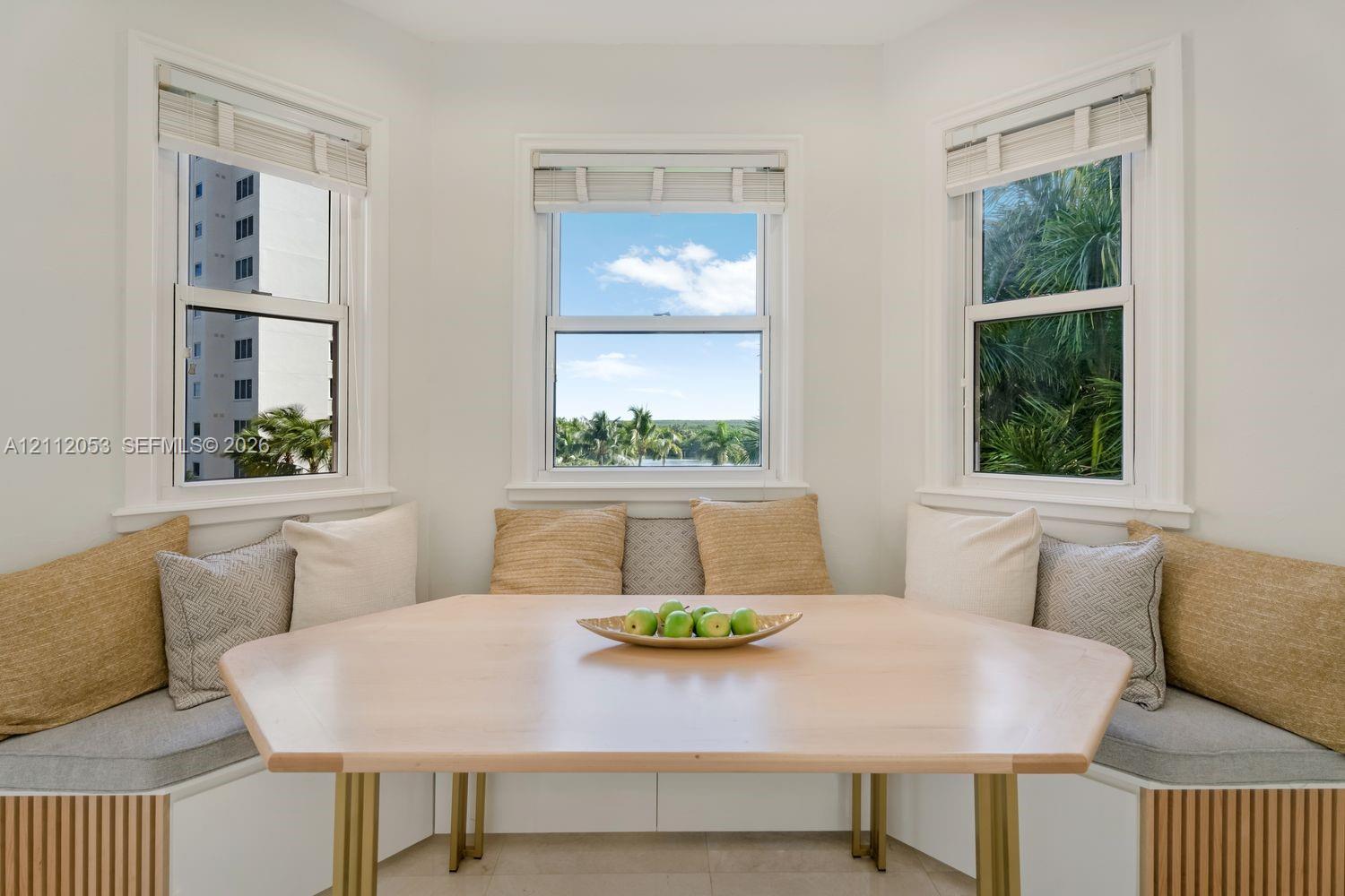 Built-in breakfast nook with custom slatted wood-finish base cabinetry, bay window configuration, triple-pane window arrangement, and tile flooring