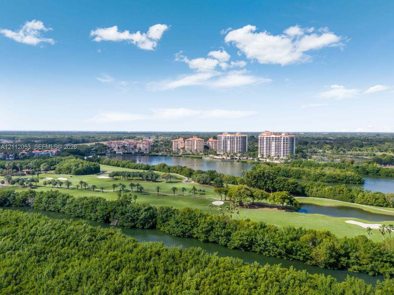 Aerial perspective featuring expansive fairways, multiple water hazards, mature vegetation, and high-rise structures