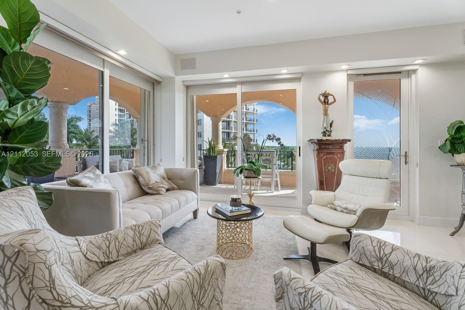 Living area featuring floor-to-ceiling glass sliding doors, recessed lighting, and polished stone flooring, opening to a covered terrace with decorative columns Living area featuring floor-to-ceiling glass sliding doors, recessed lighting, and polished stone flooring, opening to a covered terrace with decorative columns