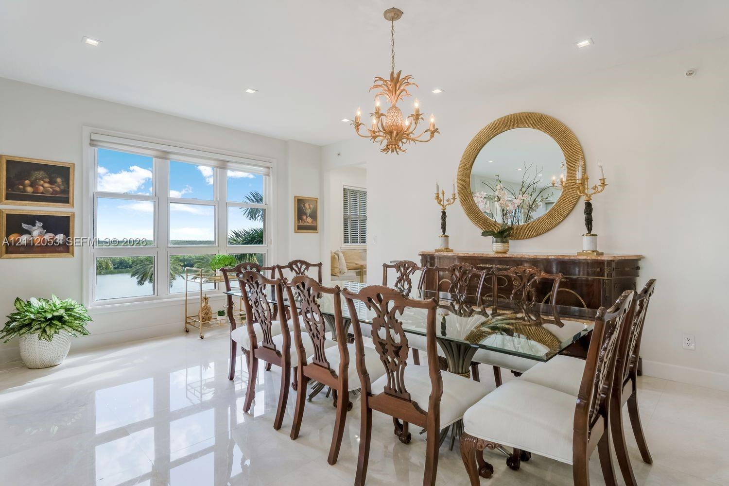 Dining area featuring polished stone flooring, large-scale multi-pane windows, recessed ceiling lighting, and a decorative gold-tone chandelier
