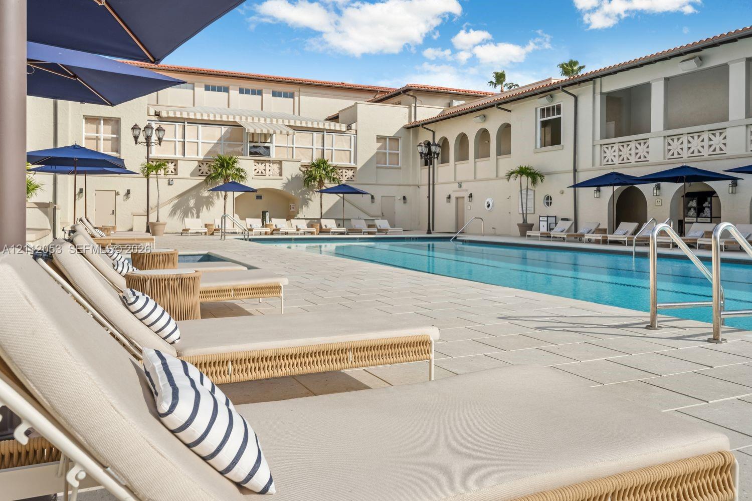 Swimming pool with stone-tiled patio, architectural arches, and exterior lighting fixtures