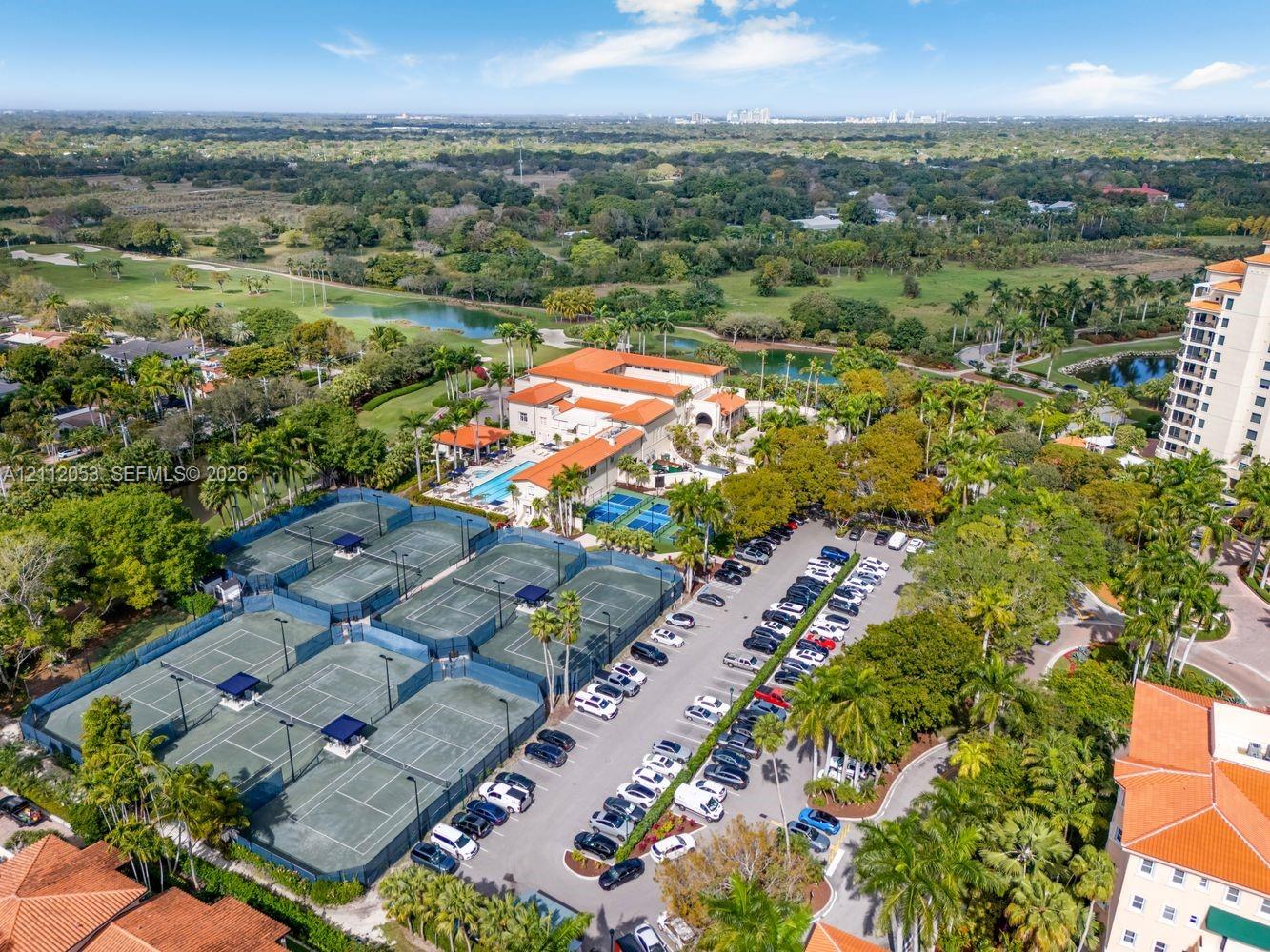 Tennis facility featuring multiple courts, paved surface parking, and outdoor swimming pool