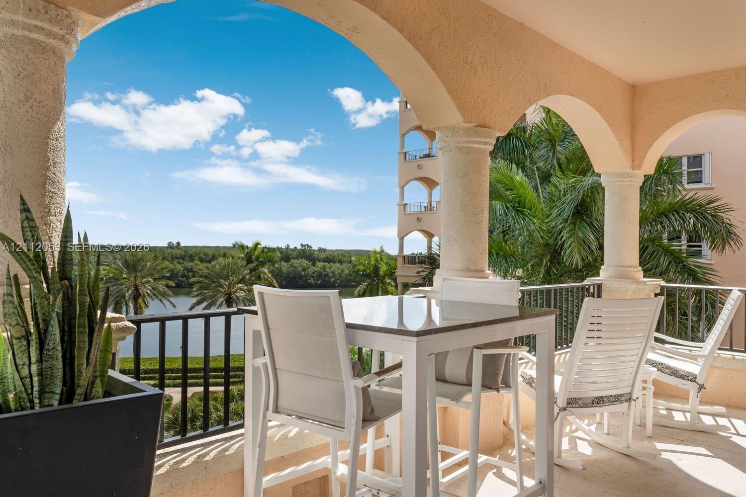 Covered balcony featuring arched masonry architecture, decorative columns, a black metal railing, and stone flooring Covered balcony featuring arched masonry architecture, decorative columns, a black metal railing, and stone flooring