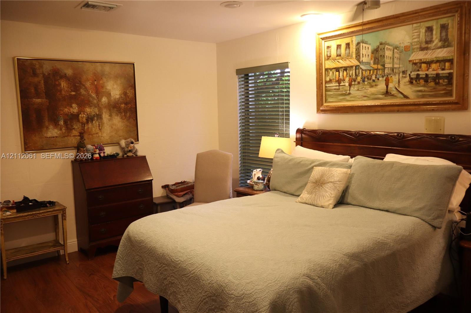 Interior room featuring wood-finish flooring and horizontal window blinds Interior room featuring wood-finish flooring and horizontal window blinds