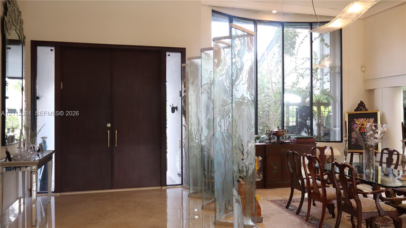 Double-door entry with sidelights, high ceilings, expansive floor-to-ceiling curved windows, and decorative frosted glass panels Double-door entry with sidelights, high ceilings, expansive floor-to-ceiling curved windows, and decorative frosted glass panels