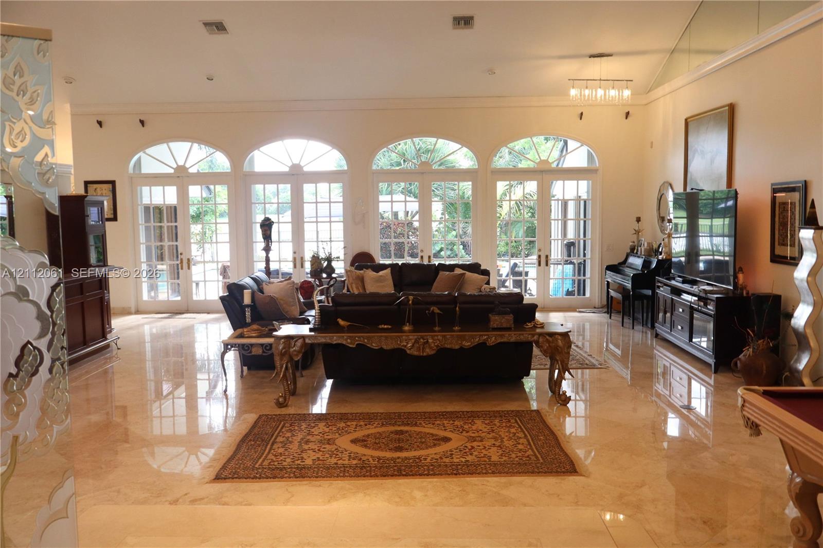 Polished stone flooring, high ceilings, and four sets of arched French glass doors Polished stone flooring, high ceilings, and four sets of arched French glass doors