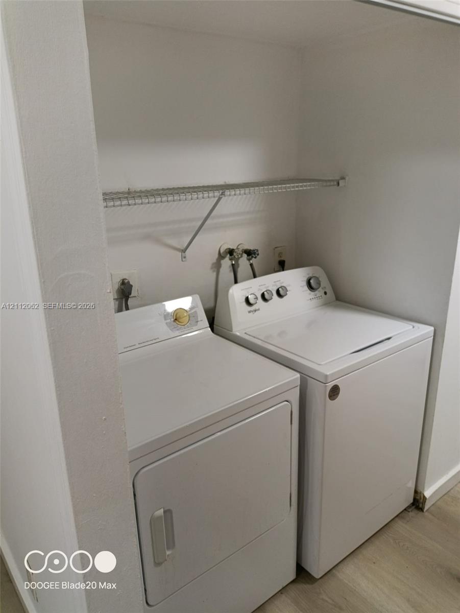 Laundry alcove featuring wood-finish flooring and a wire shelving unit