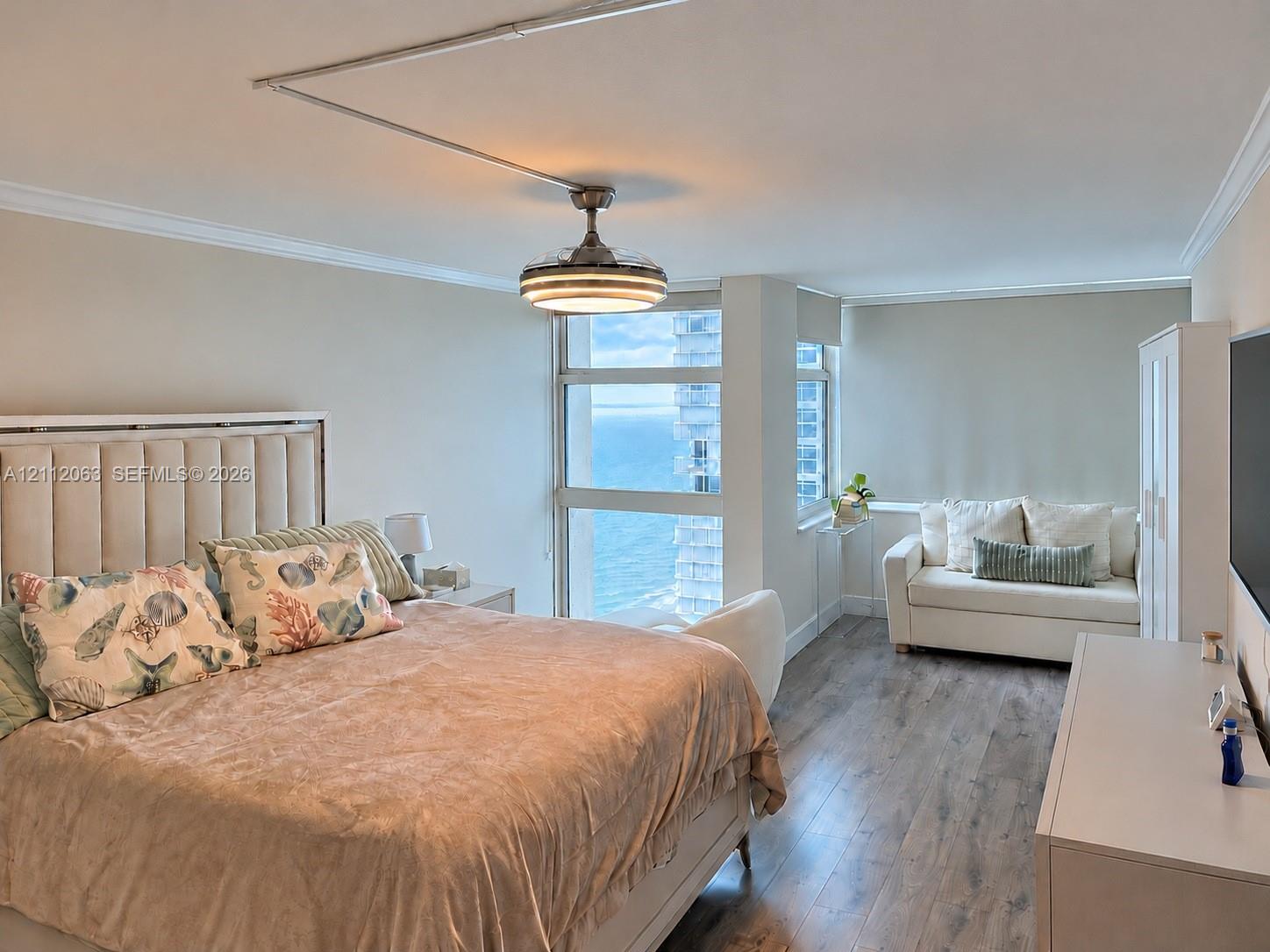 Floor-to-ceiling windows with water orientation, wood-finish flooring, and crown molding Floor-to-ceiling windows with water orientation, wood-finish flooring, and crown molding