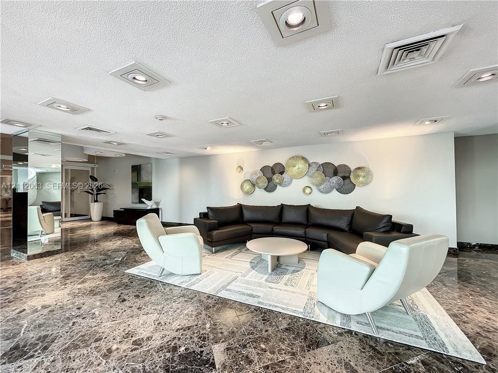 Spacious interior featuring polished stone flooring, recessed ceiling lighting, and mirrored structural columns