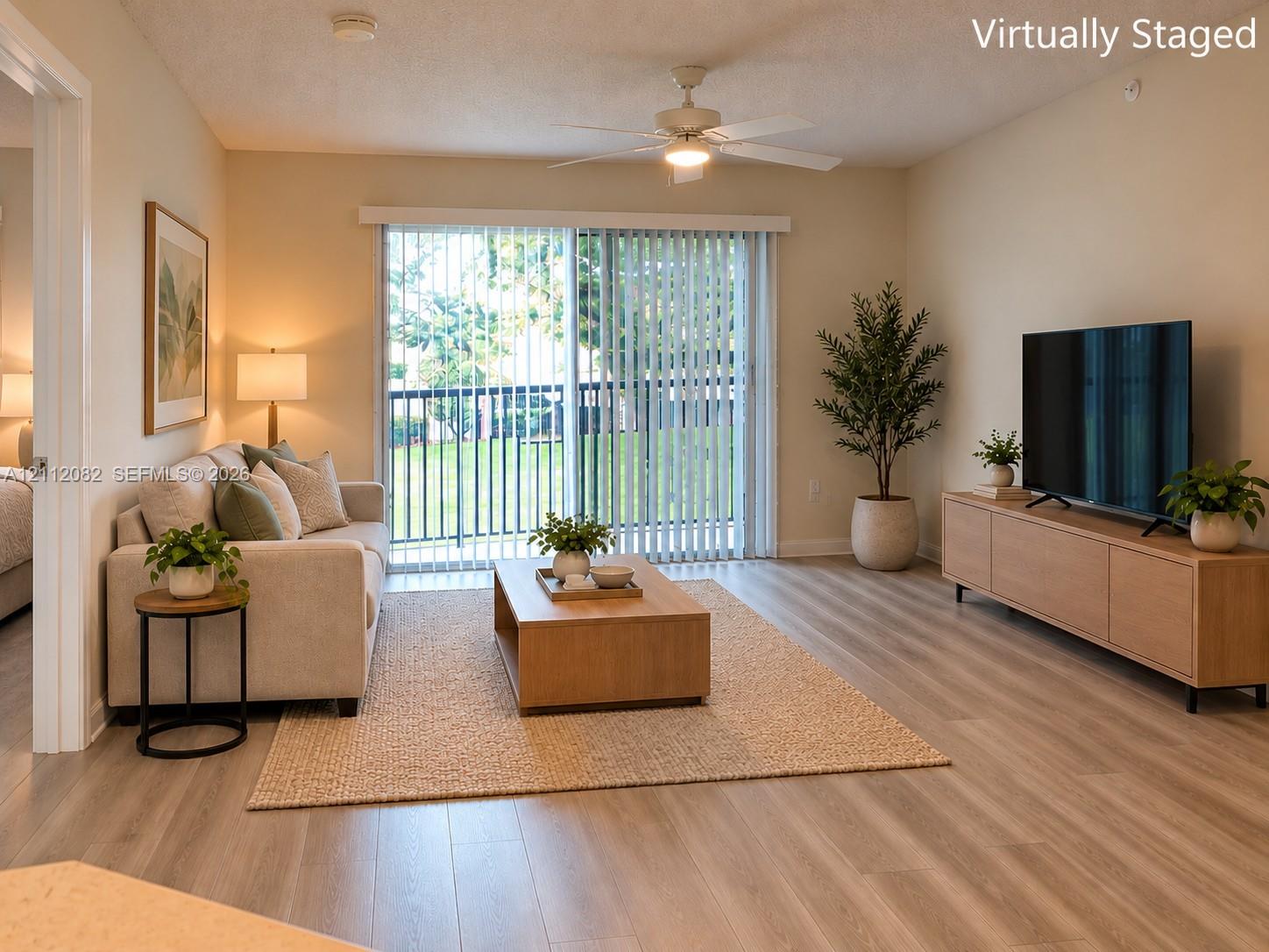 Living area featuring wood-finish flooring, a ceiling fan with integrated lighting, and a sliding glass door providing external access