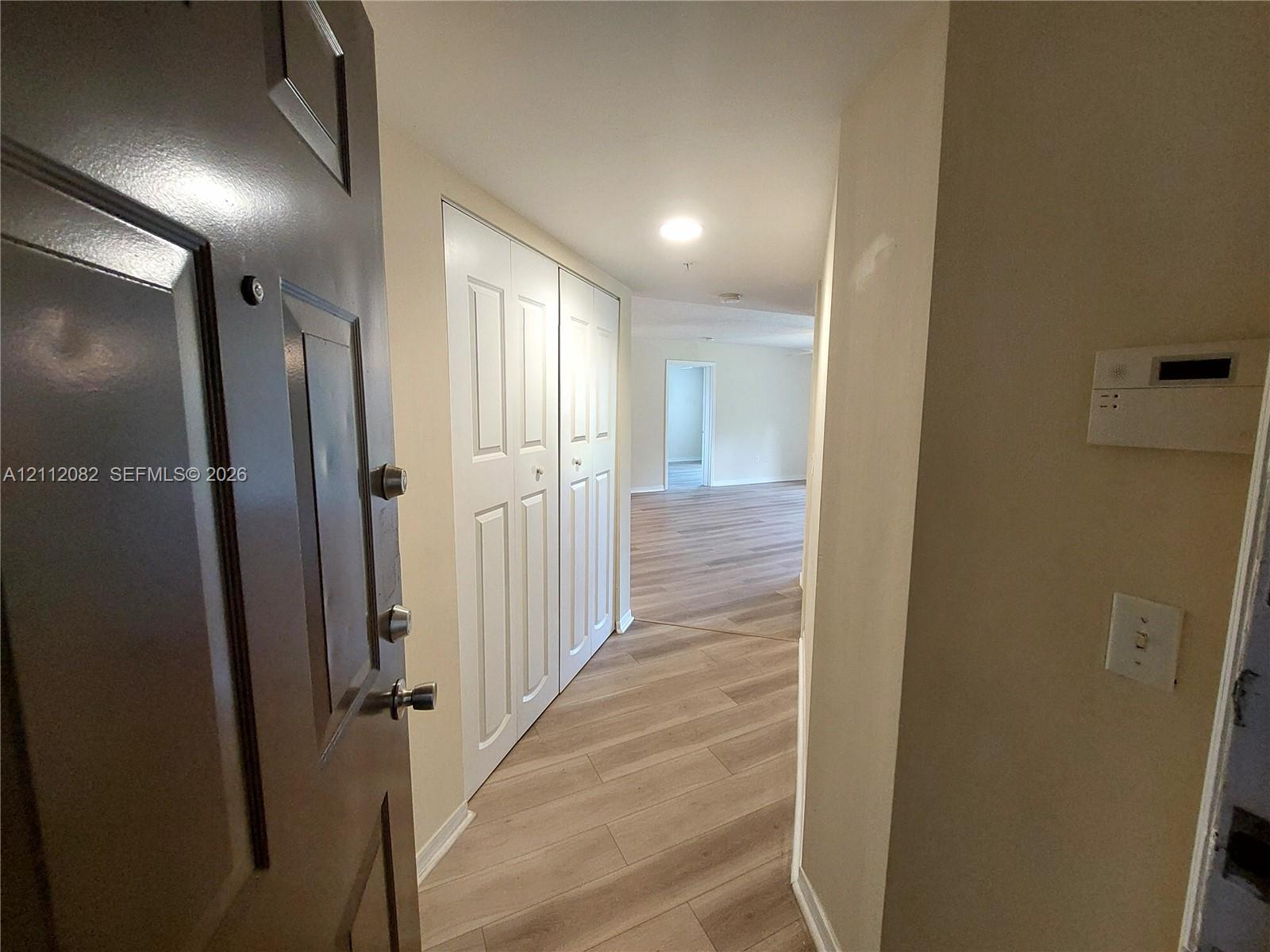 Entryway featuring wood-finish flooring, white panel closet doors, and recessed lighting