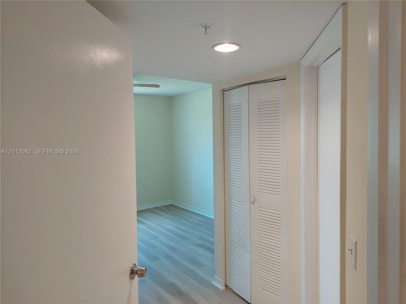 Hallway featuring wood-finish flooring, recessed lighting, and a white bifold louvered closet door