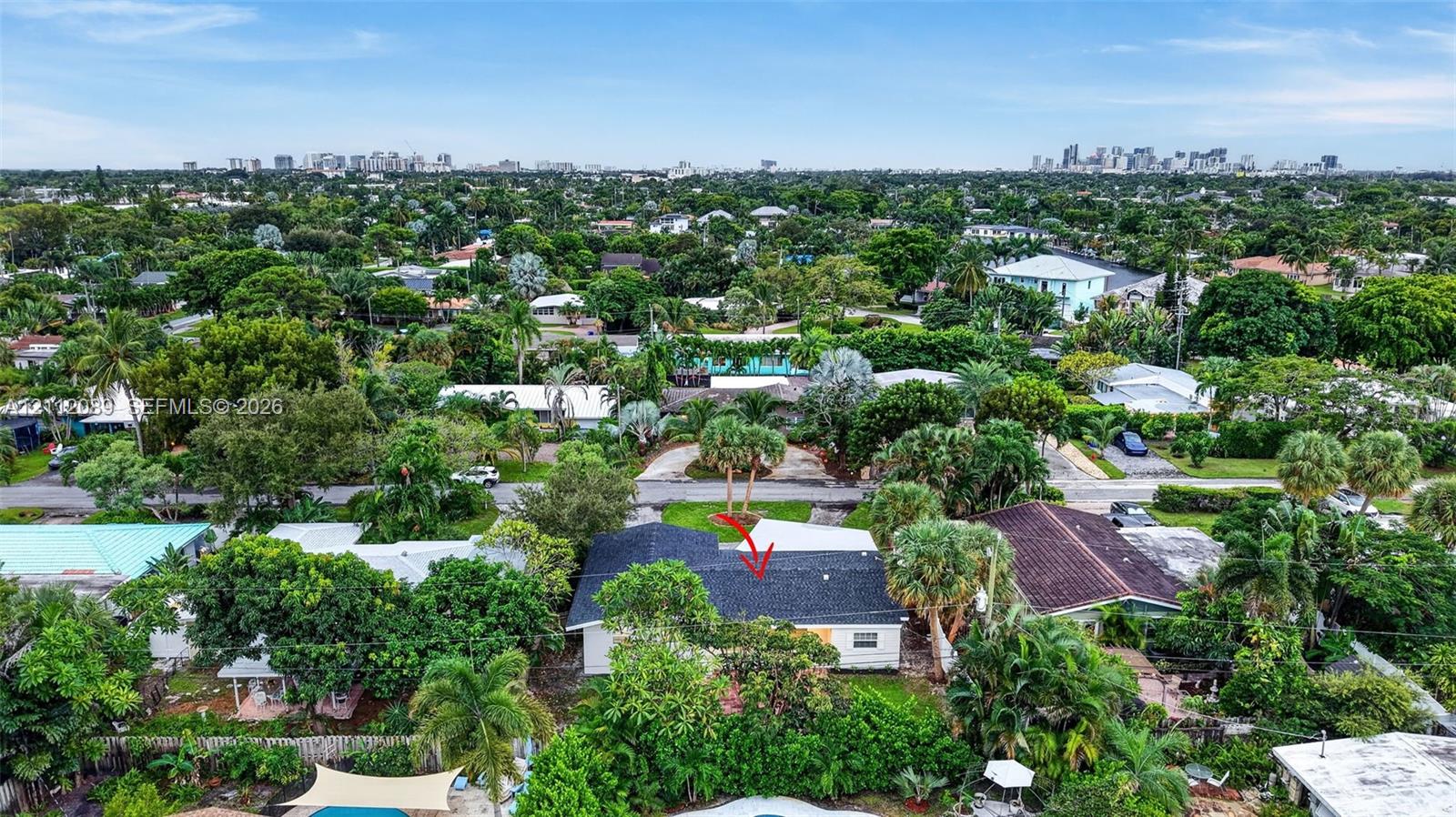 Aerial perspective of property featuring a dark-toned shingle roof, mature tropical vegetation, and extensive surrounding tree canopy