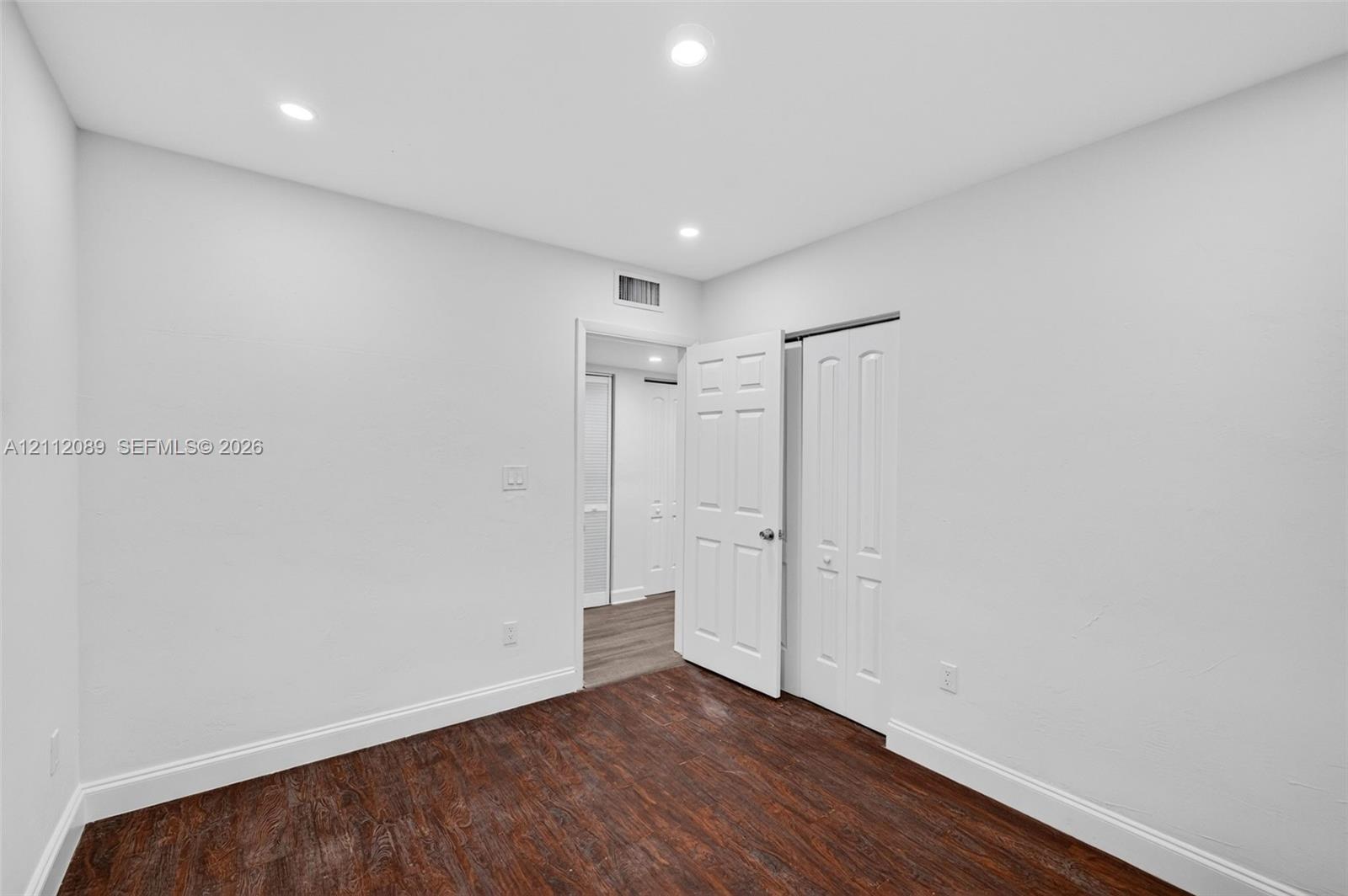 Interior space featuring dark wood-finish flooring, recessed lighting, and white paneled doors