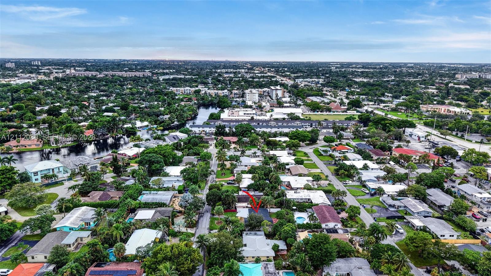 Aerial perspective of a residential property featuring a rectangular swimming pool, fenced perimeter, and mature landscape vegetation