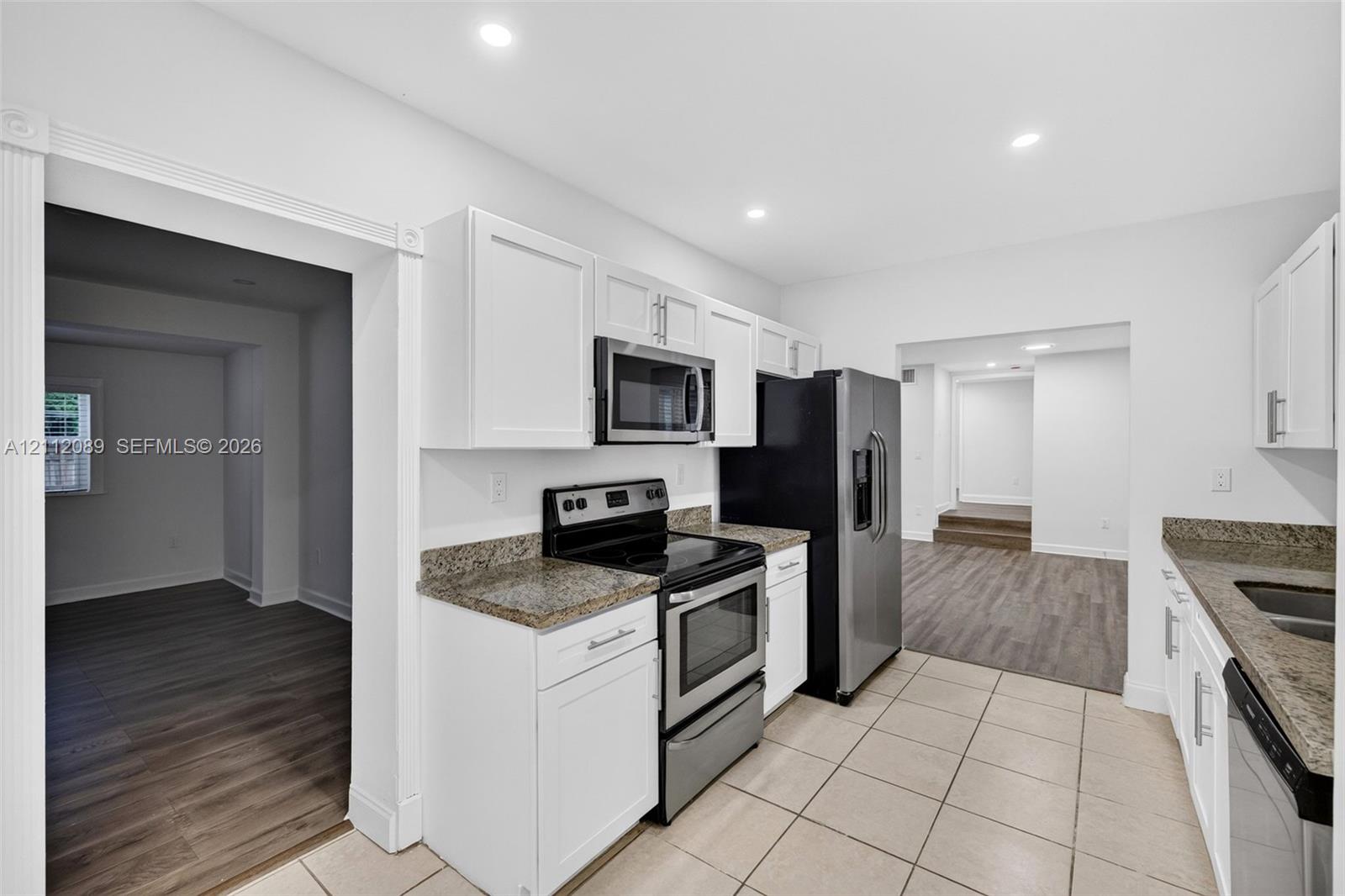 Kitchen featuring white cabinetry, stone-finish countertops, stainless steel appliances, and tile flooring