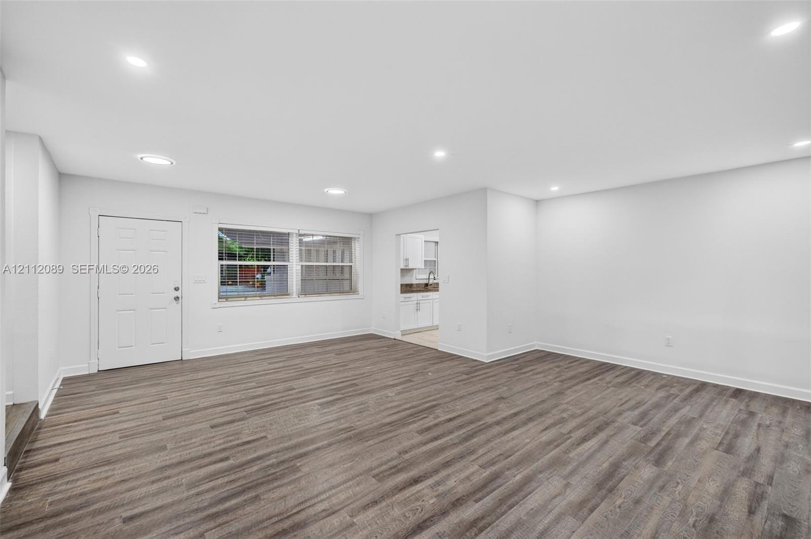 Open-concept room featuring wood-finish flooring, recessed lighting, and a multi-pane window
