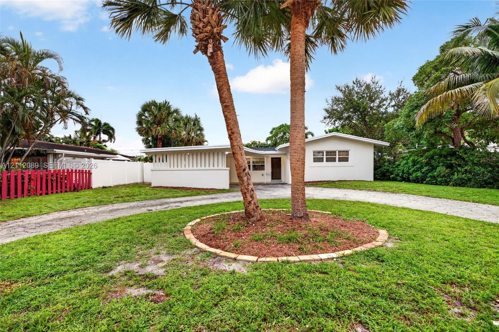 Single-story exterior featuring white stucco siding, a curved driveway, and a decorative slatted privacy screen