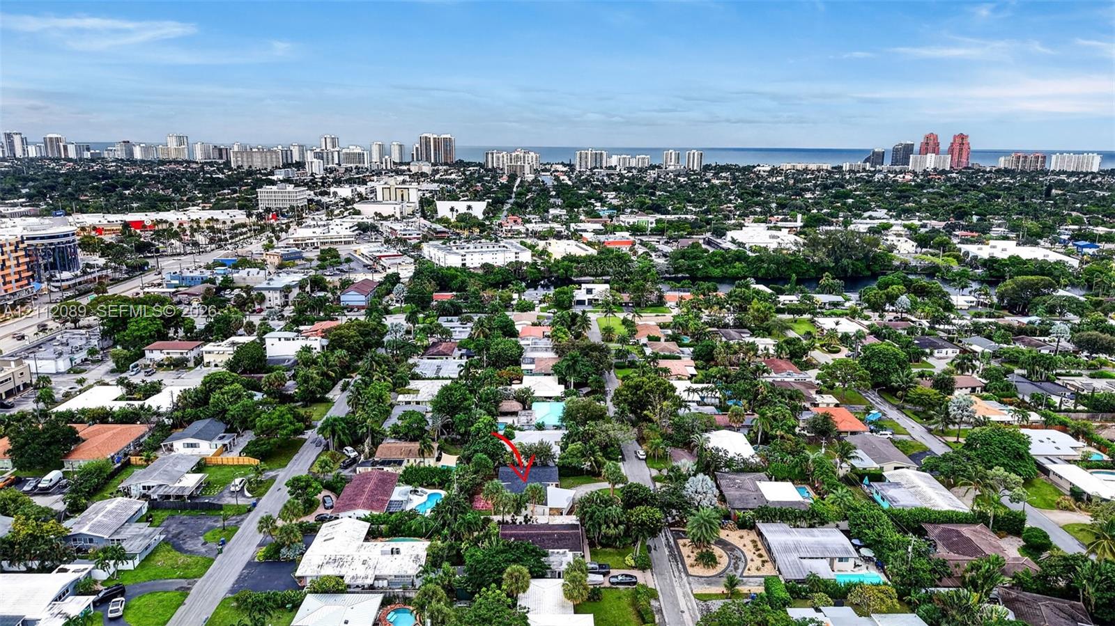 Aerial perspective of the property featuring mature landscaping and a roofline designated by marker, situated within a coastal urban environment