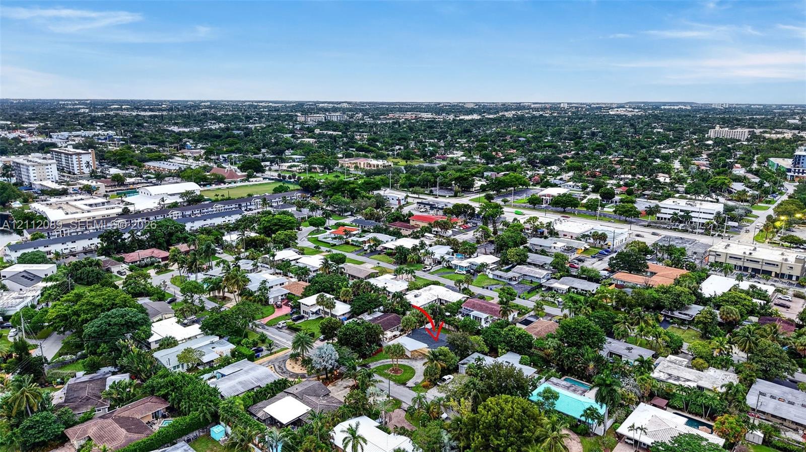 Aerial perspective of a residential property situated in a suburban setting with mature canopy trees and established landscaping