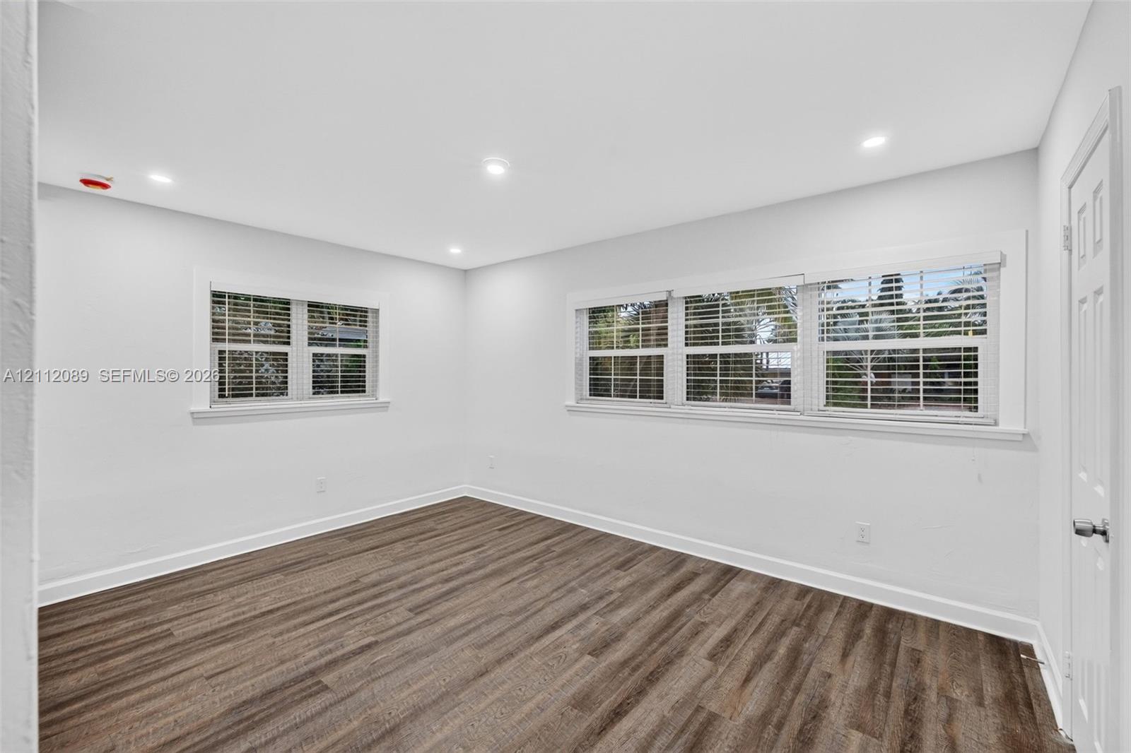 Interior room featuring wood-finish flooring, recessed lighting, and windows with white casings